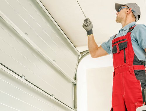 Modern Automatic Garage Doors Installation Performed by Professional Caucasian Installer. Residential Automation.